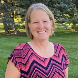 “Lori Tschetter, CSW, smiling outdoors in a professional photo, wearing a patterned pink and navy top.”